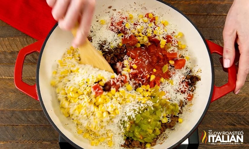 mixing Mexican taco rice ingredients together in a skillet