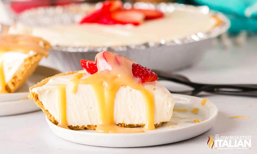 slice of no bake cheesecake drizzled with caramel sauce and topped with sliced strawberries