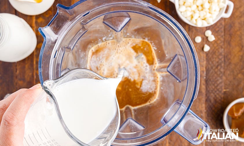 pouring milk into a blender with espresso