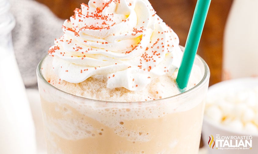 close up: homemade white mocha frappuccino topped with whipped cream and red sanding sugar