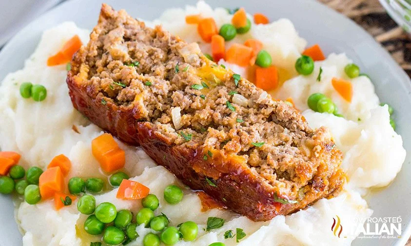 slice of meatloaf on mashed potatoes with mixed vegetables