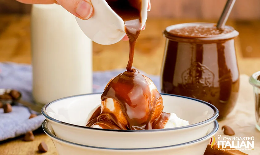 pouring hot fudge sauce over scoops of ice cream in bowl