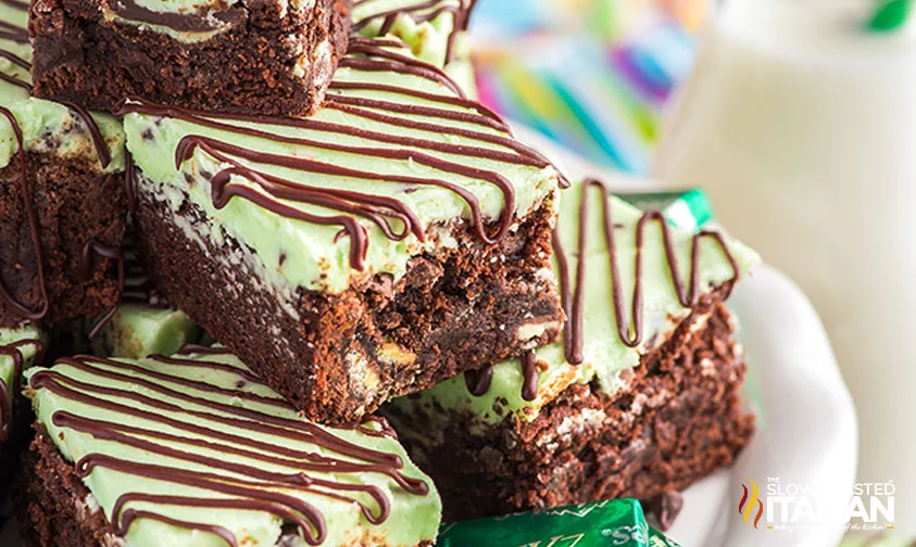 frosted mint chocolate brownies stacked on a plate with Andes mints
