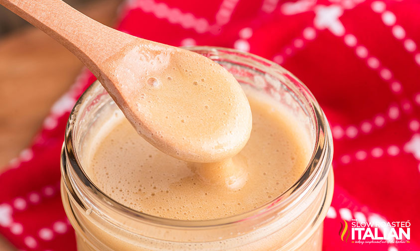 wooden spoon dipped in a glass jar full of homemade maple cream