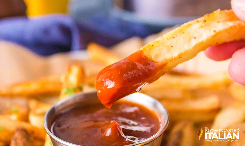 closeup: homemade french fry dipped in ketchup