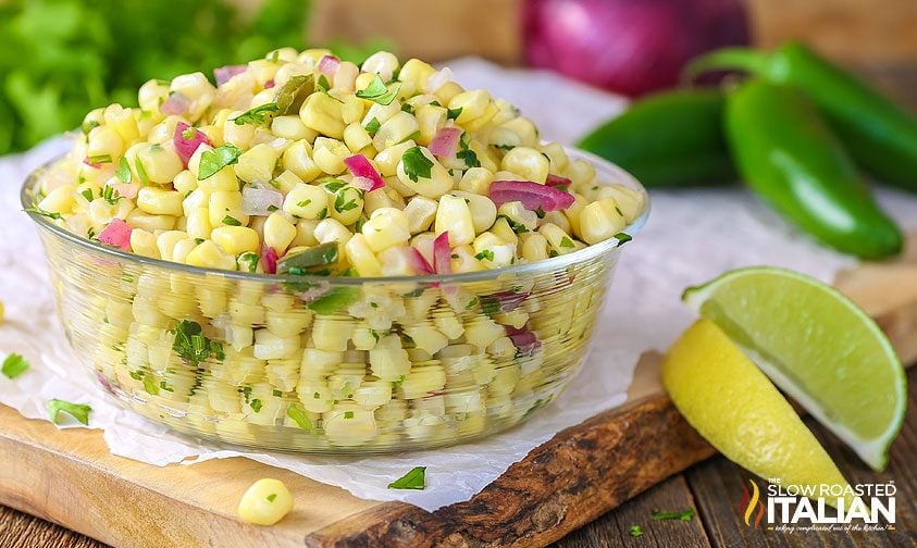 bowl of corn salsa like chipotle surrounded by limes and jalapenos