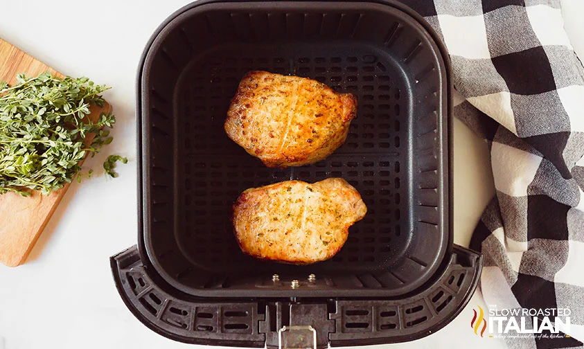 two boneless pork chops in air fryer basket