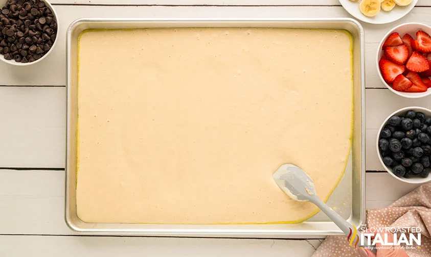 spreading pancake batter into sheet pan with spatula