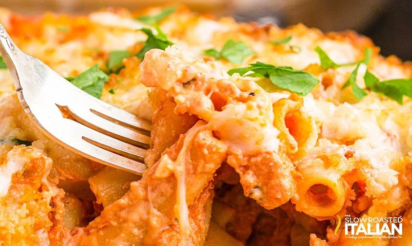 digging a fork into copycat ziti al forno topped with parsley