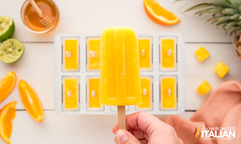 hand holding a pineapple orange popsicle