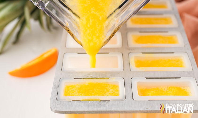 poring blended oranges and pineapples into ice pop molds