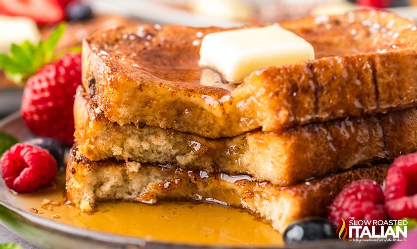 3 slices of sheet pan french toast stacked with butter and syrup
