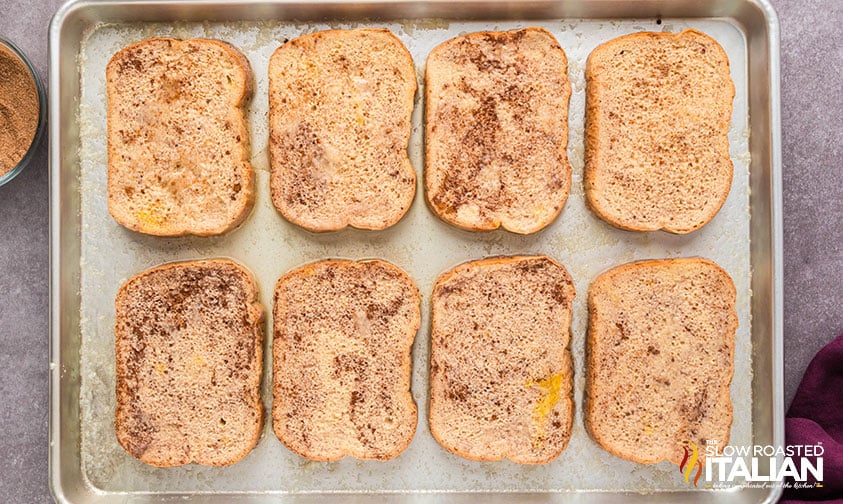 bread slices dipped in egg mixture and sprinkled with cinnamon sugar on a sheet pan