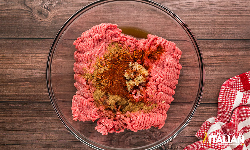 mixing ground beef and seasoning in a large bowl