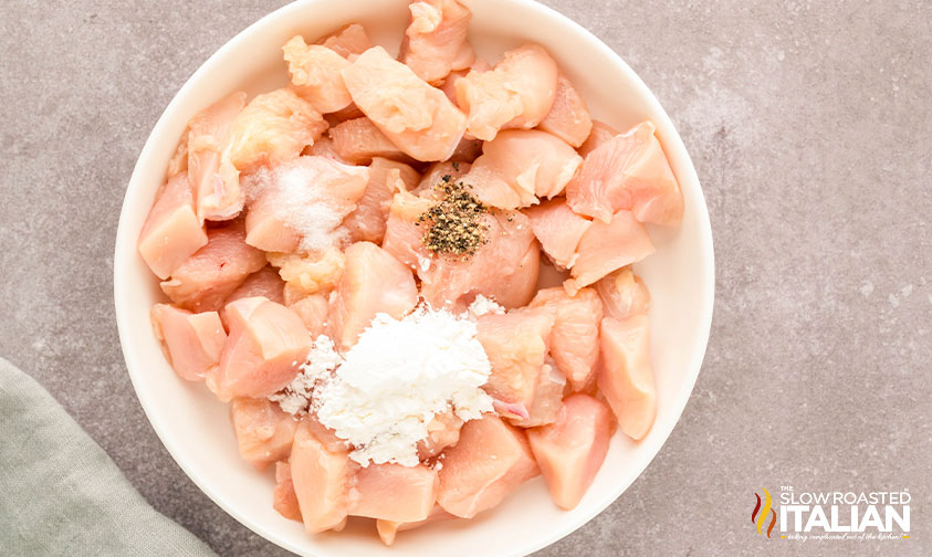 adding cornstarch, salt and pepper to chicken pieces