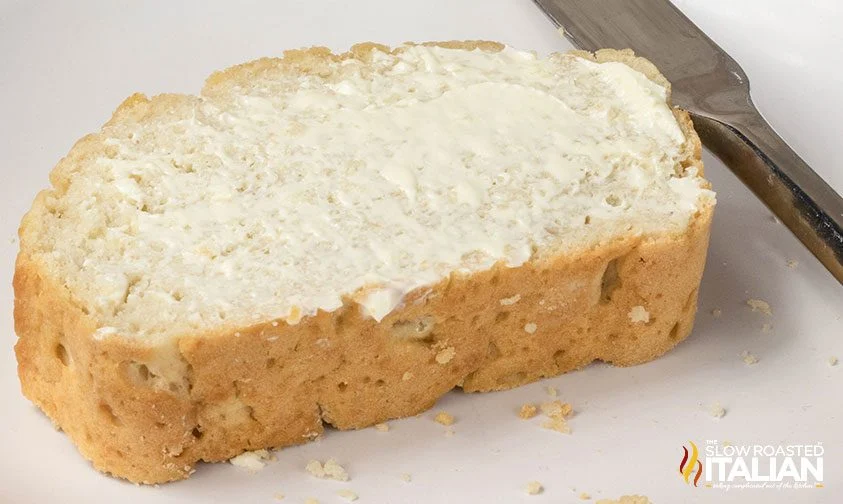 close up: thick slice of beer bread slathered in butter