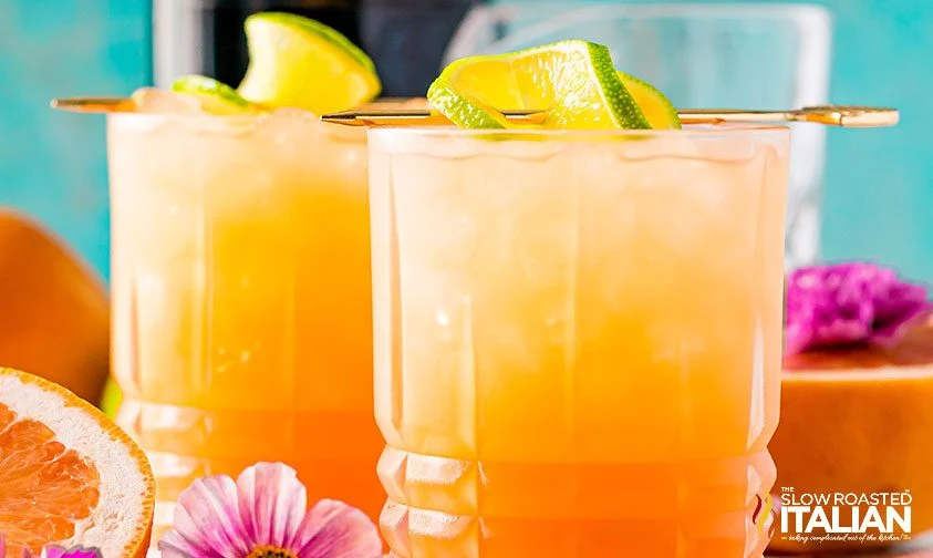 two greyhound cocktails with twist of lime on cocktail skewer resting on glass