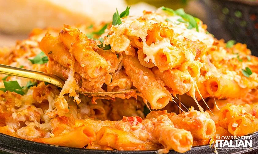close up: scooping 5 cheese ziti al forno from skillet