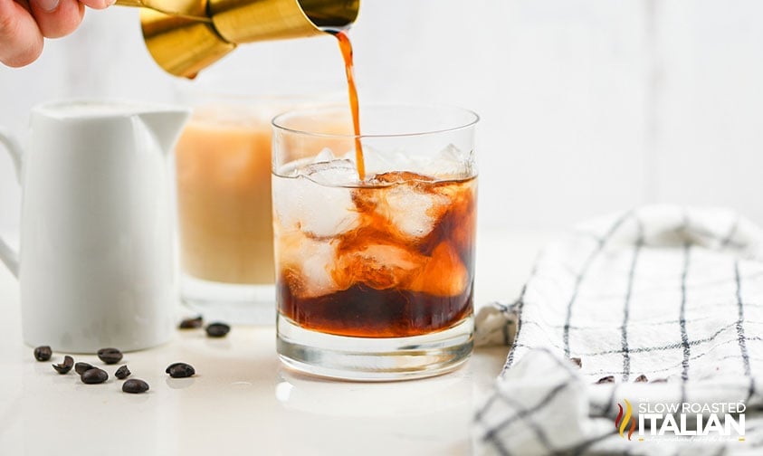 pouring coffee liqueur into glass of ice and vodka