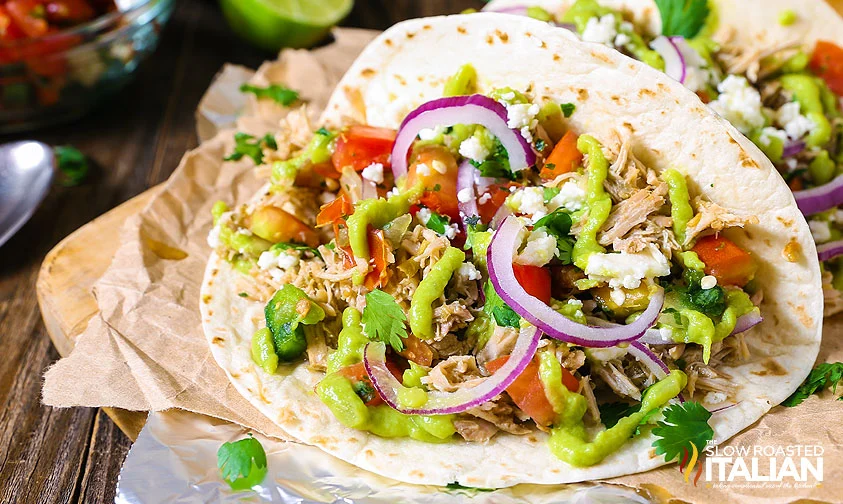 pork carnitas taco with red onion, guacamole, and tomatoes