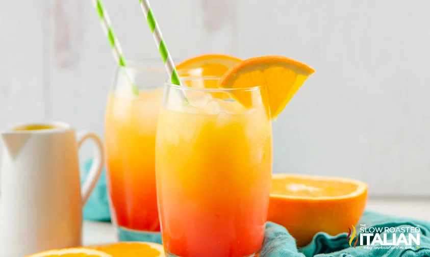 two tequila sunrise drinks with paper straws and orange slices