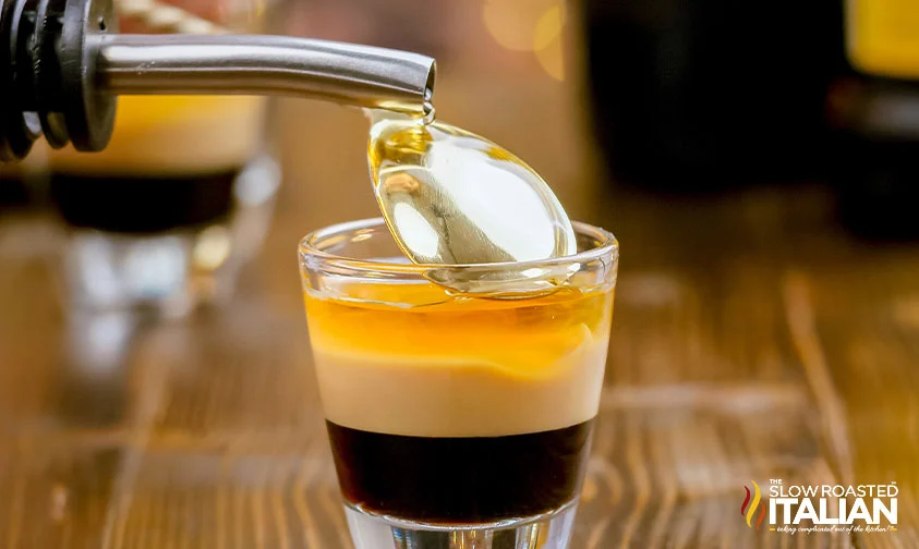 finishing B52 drink with Grand Marnier poured over the back of a spoon into shot glass