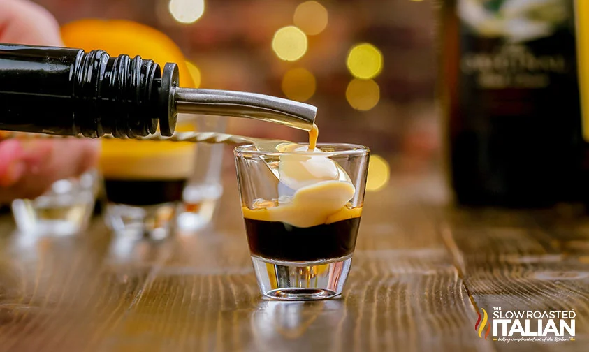 pouring Kahlua over the back of a spoon into shot glass with kahlua
