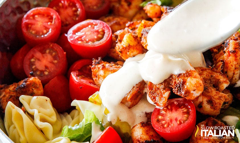 extreme closeup: adding remoulade dressing to shrimp tortellini salad
