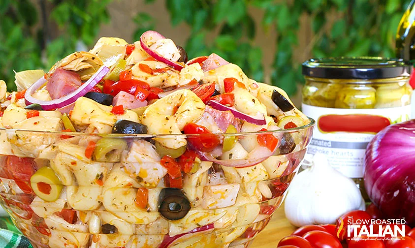 large bowl of antipasto salad with tortellini on a table outside
