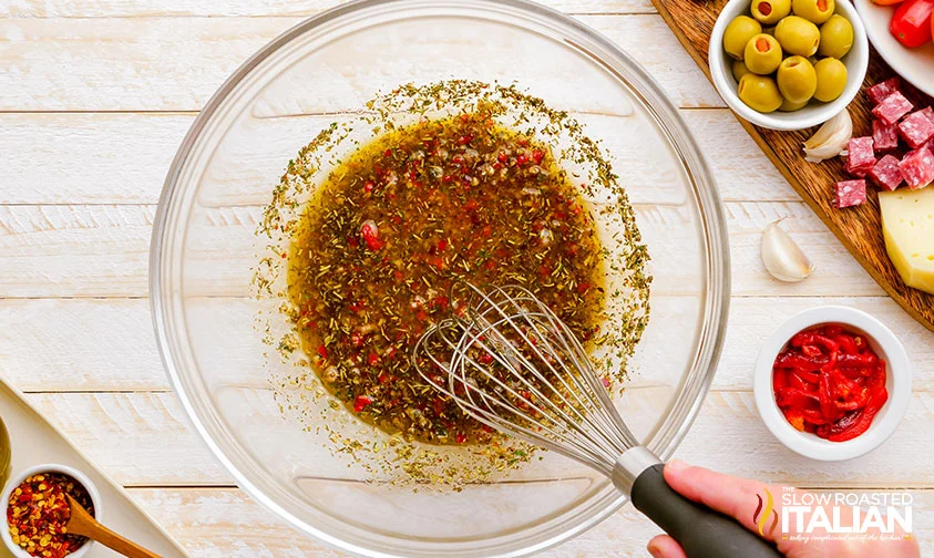 whisking Italian dressing in a bowl for antipasto salad