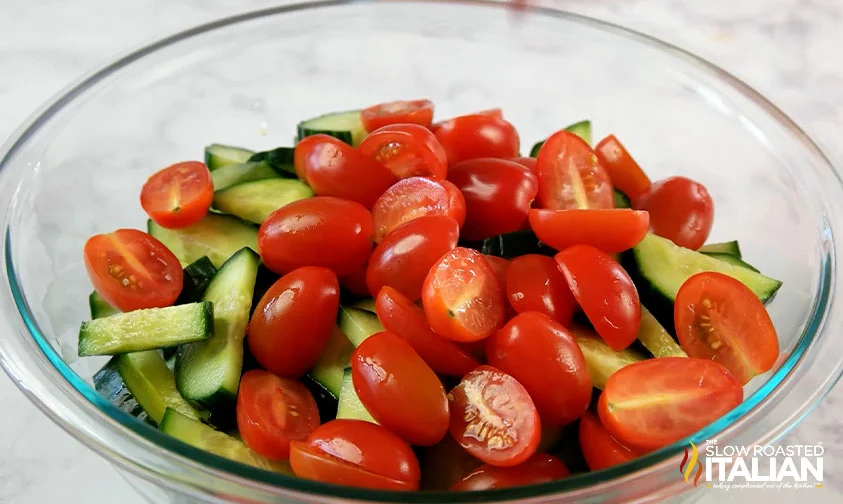 sliced cucumbers and cherry tomatoes in a clear bowl