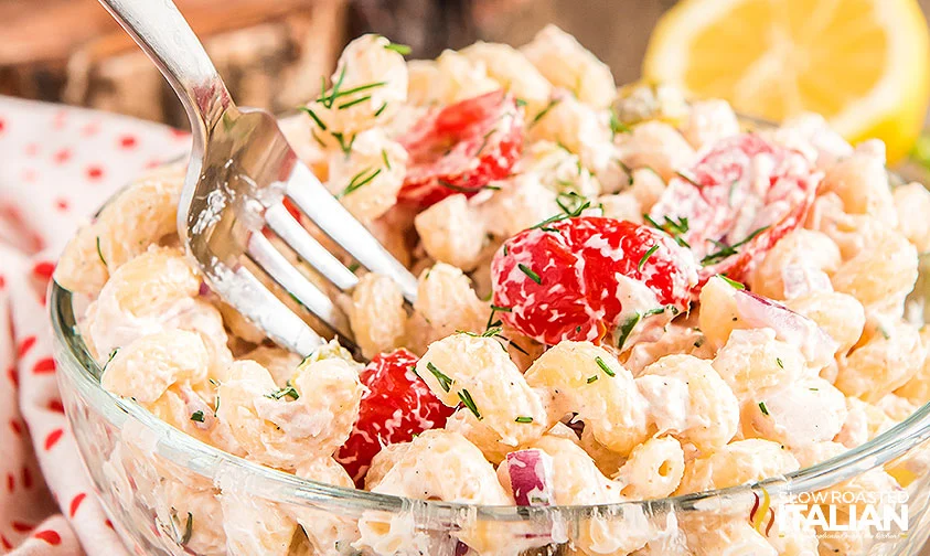 fork in a bowl of creamy tuna pasta salad with tomatoes