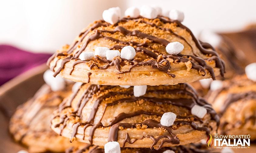 stack of s'mores hand pies drizzing with chocolate and topped with tiny marshmallows