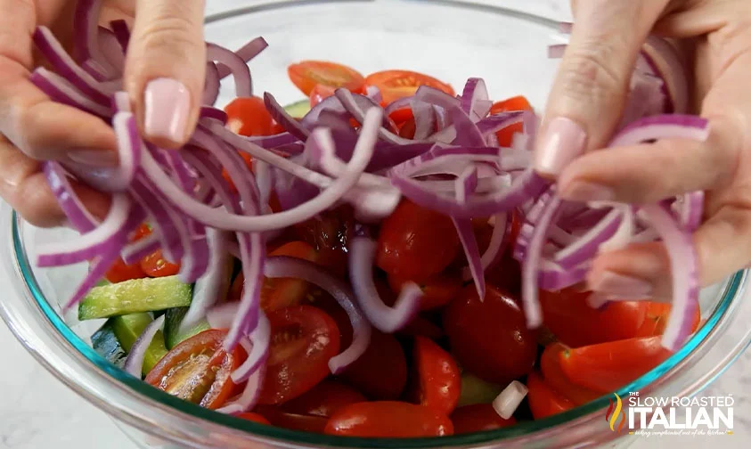 add red onion slices to bowl with cucumbers and tomatoes