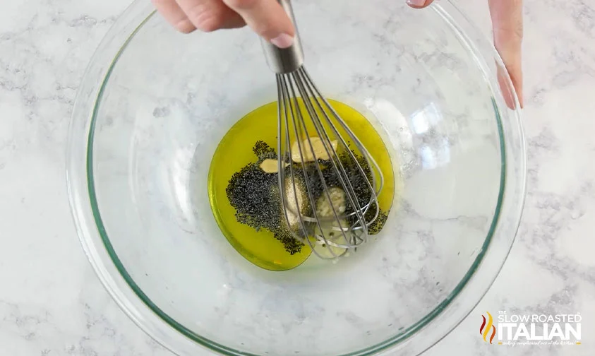 whisking lemon poppyseed dressing ingredients in a clear bowl
