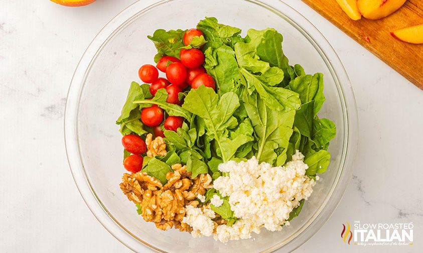 adding grilled peach salad ingredients to a large mixing bowl