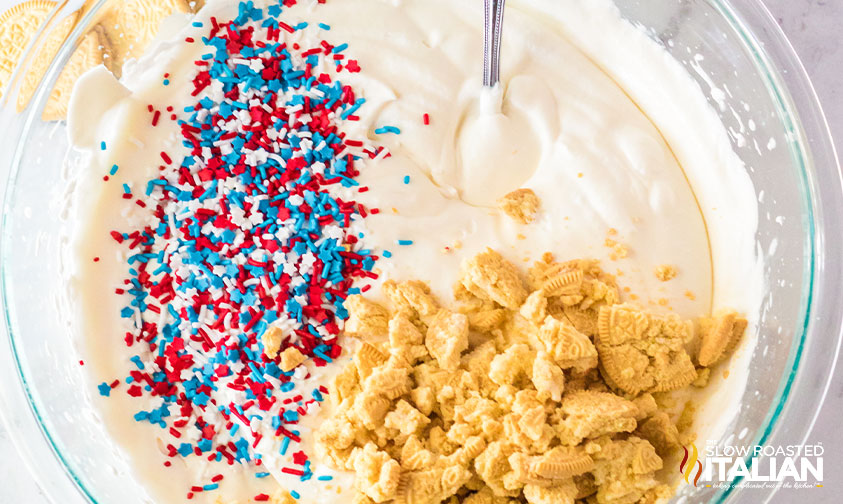 adding crushed cookies and sprinkles to red white and blue ice cream
