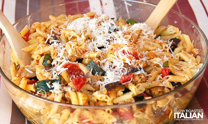 large bowl of penne pasta with roasted vegetables, topped with shredded cheese