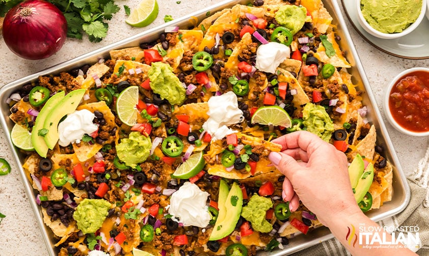 closeup of a hand with baked nachos