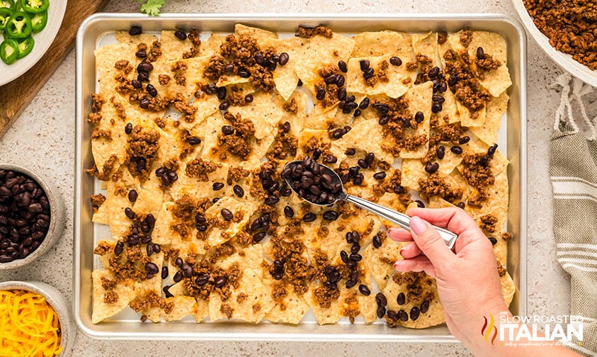 tortilla chips, ground beef, and beans on a sheet pan