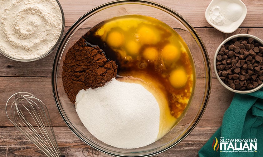 adding eggs, sugar, cocoa powder and vanilla extract to melted butter