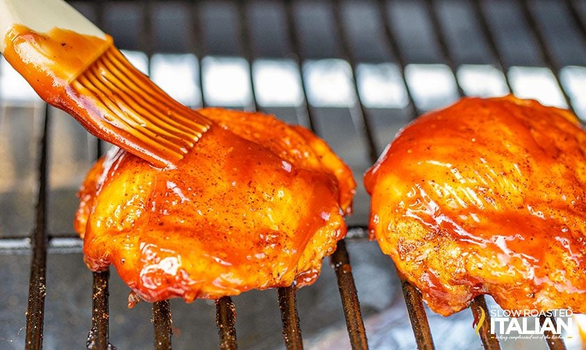 closeup: brushing smoked chicken thighs recipe with barbecue sauce
