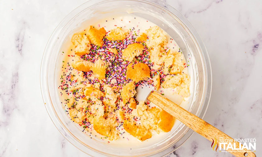 mixing vanilla cupcake pieces and sprinkles into ice cream base