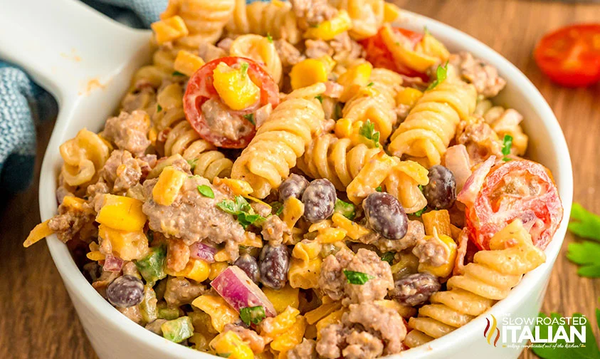 closeup: cowboy pasta salad with creamy BBQ dressing in a measuring cup