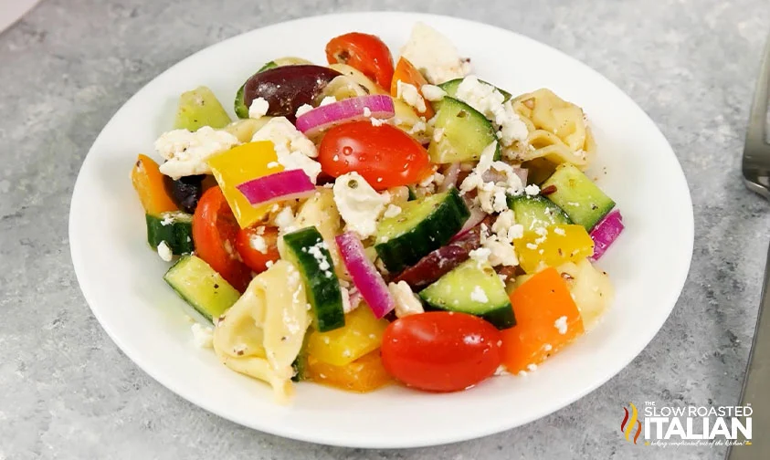 plate of greek pasta salad with tortellini, vegetables, and feta cheese