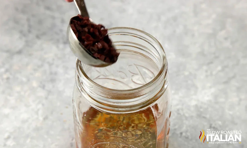 adding ingredients to jar for greek pasta salad dressing