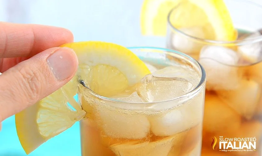 placing lemon slice on the rim of a long island iced tea cocktail