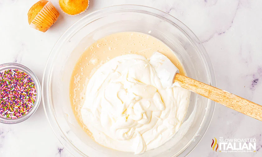 folding whipped cream into a bowl of sweetened condensed milk