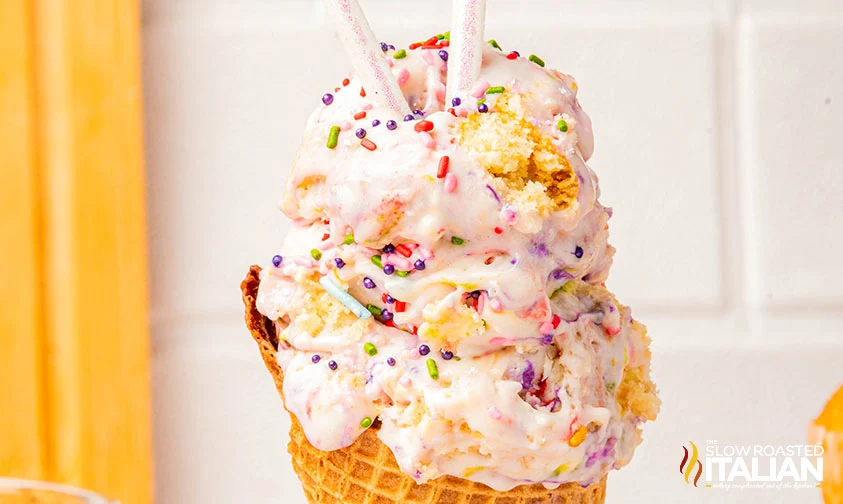 scoops of birthday cake icecream in a waffle cone with sparkly candles