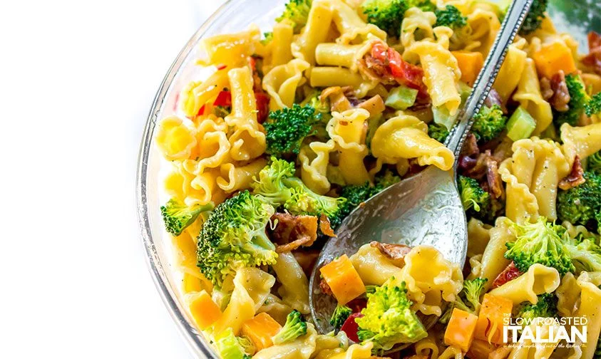 spoon resting in a bowl of broccoli and bacon pasta salad
